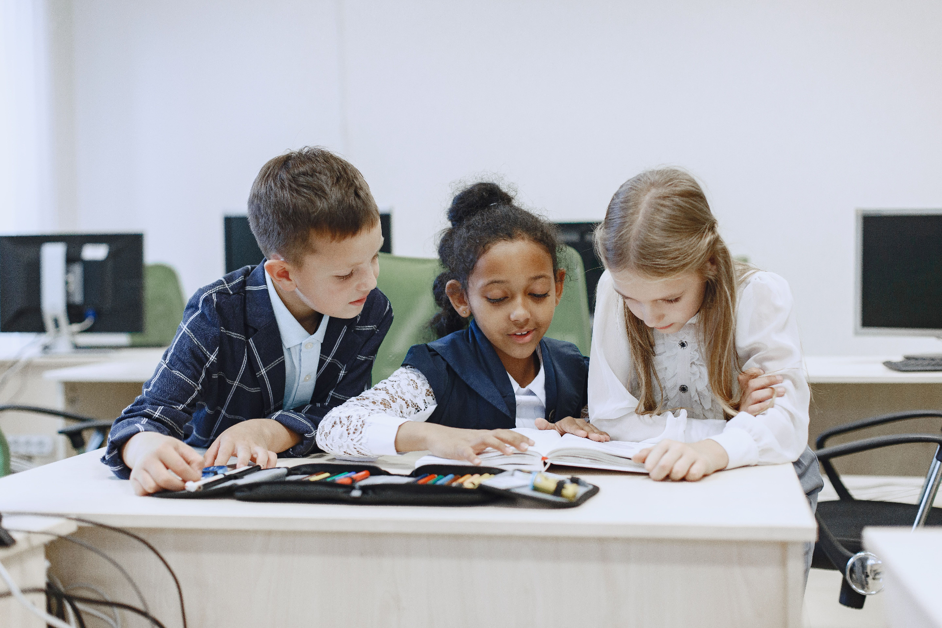 Three students reading together at a classroom table